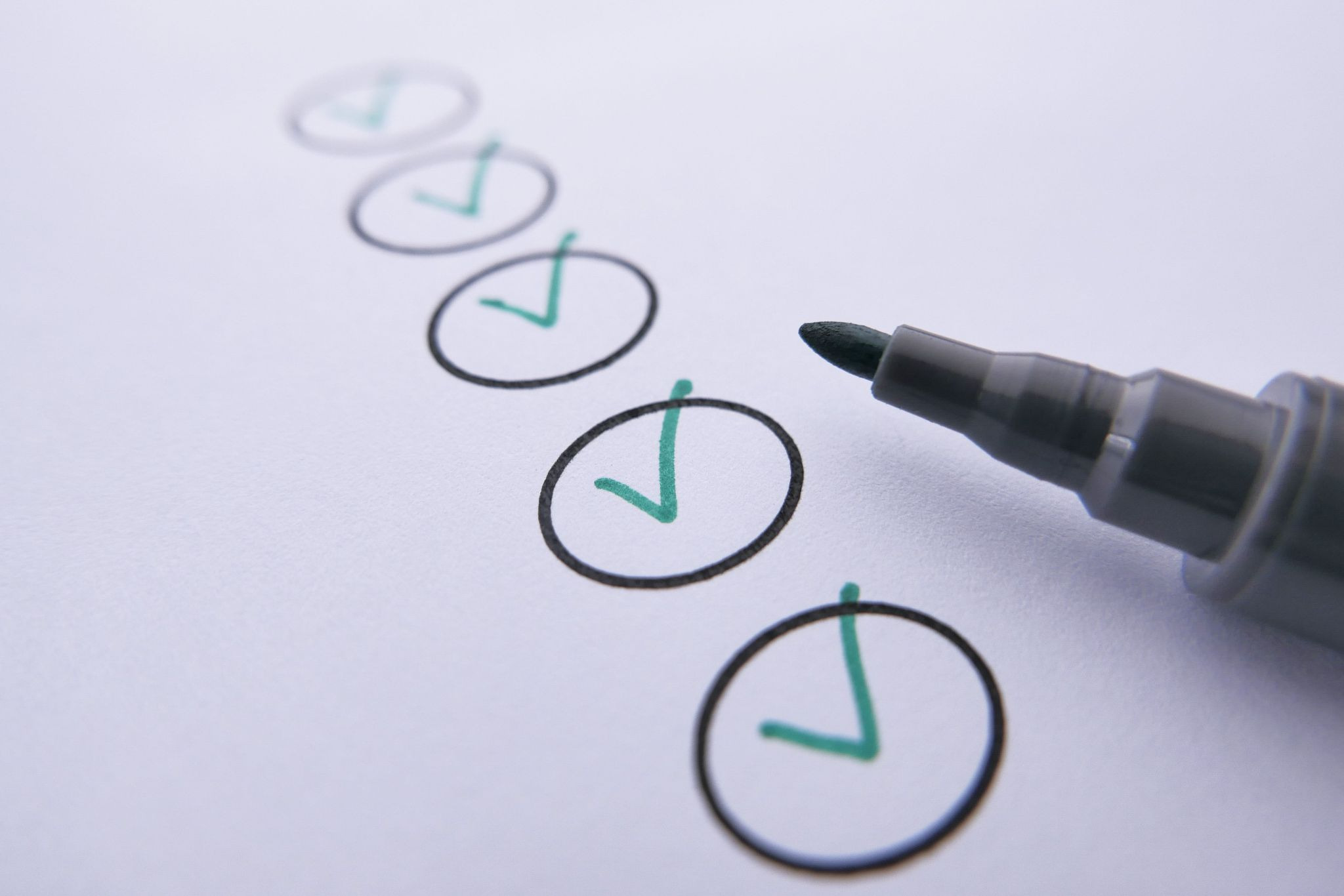 Green checkmarks inside circles on a page, with a felt marker nect to the bottom check
