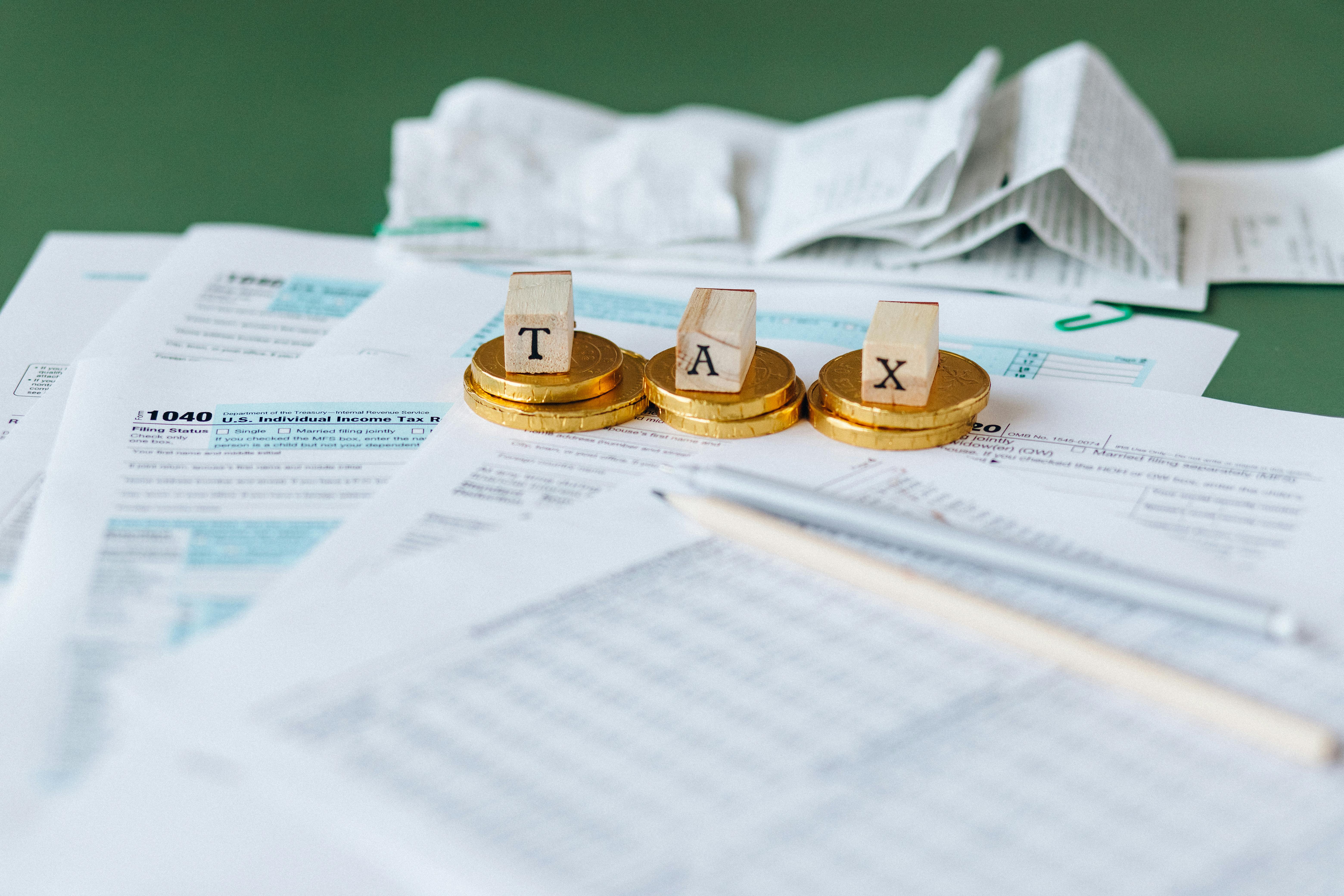 The Word, “Tax,” Spelt out on Wooden Blocks in a Row on Top of Tax Forms