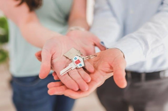 four hands holding a house key